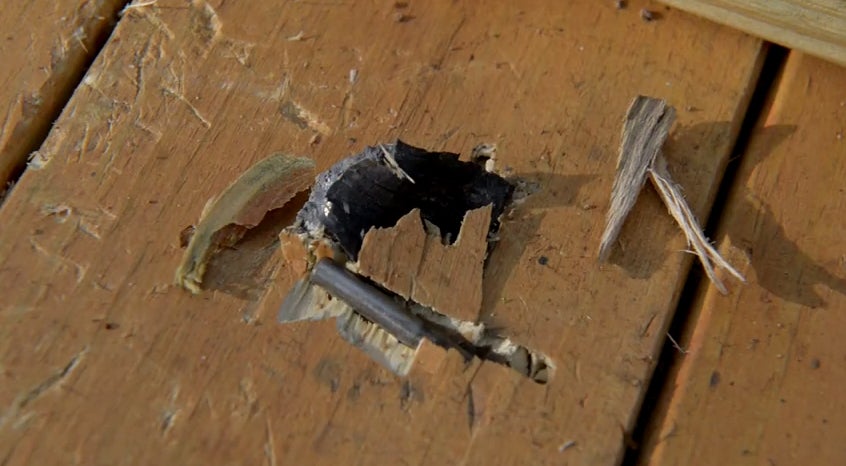 A hunk of a barrel shrapnel and a pin embedded in the shooting bench.