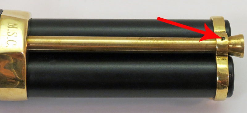 The arrow points to an itty-bitty spring loaded pin that retains the ramrod. A small tool is included to depress that pin to remove the ramrod. Photo © Russ Chastain