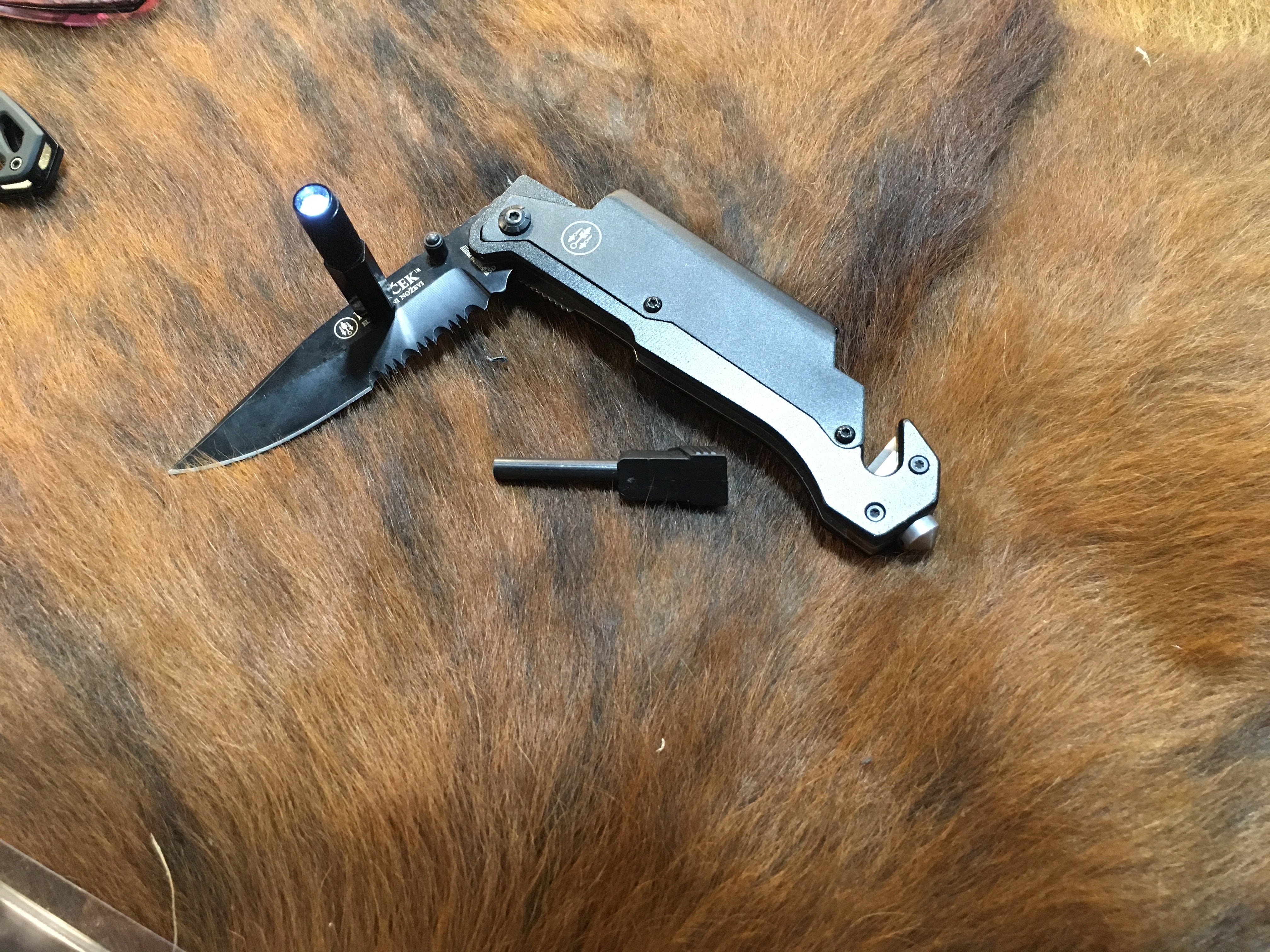 Kovacek AMZ3. It has a light, ferro rod, glass breaker and belt cutter. And, oh yeah, a knife.