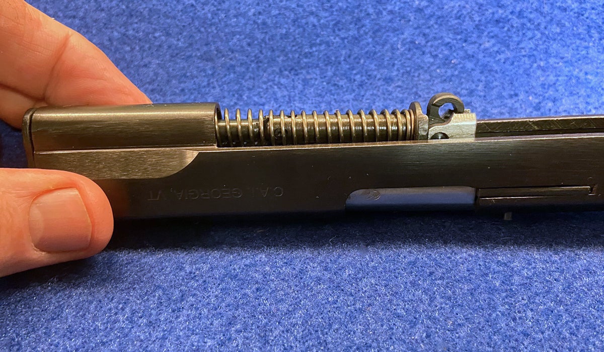 Remove the guide rod & recoil spring next, by compressing the spring slightly and lifting it at the rear. (Photo © Russ Chastain)